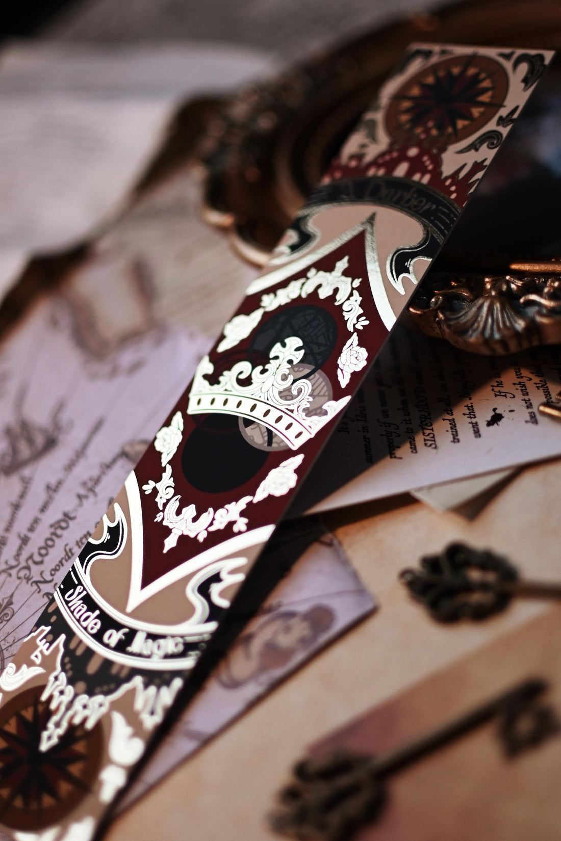 A Darker Shade of Magic book spine bookmark propped up featuring the full design with the delicate gold foil detailing. 