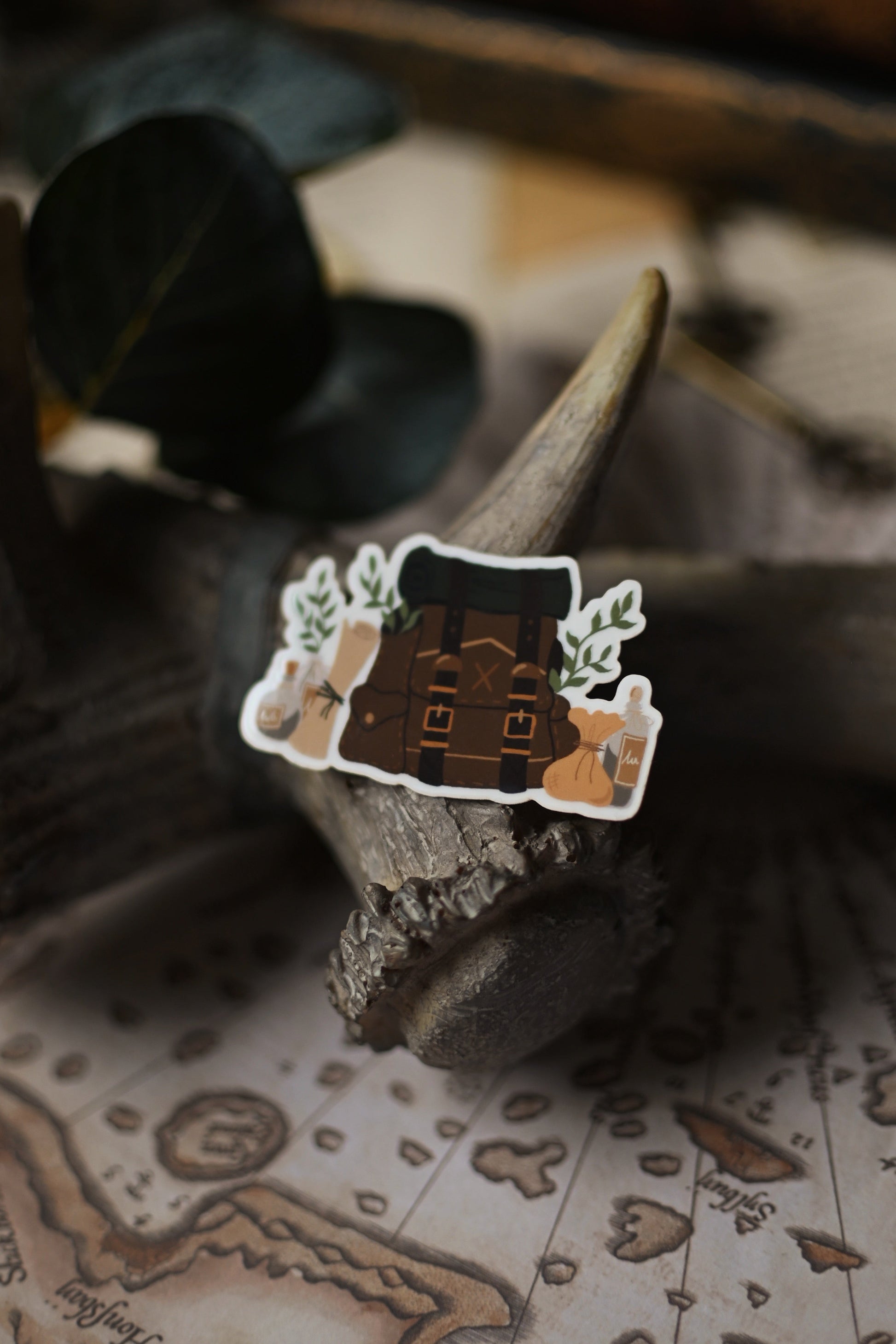 Sticker of an adventurer's backpack on a wooden surface with a map in the background.