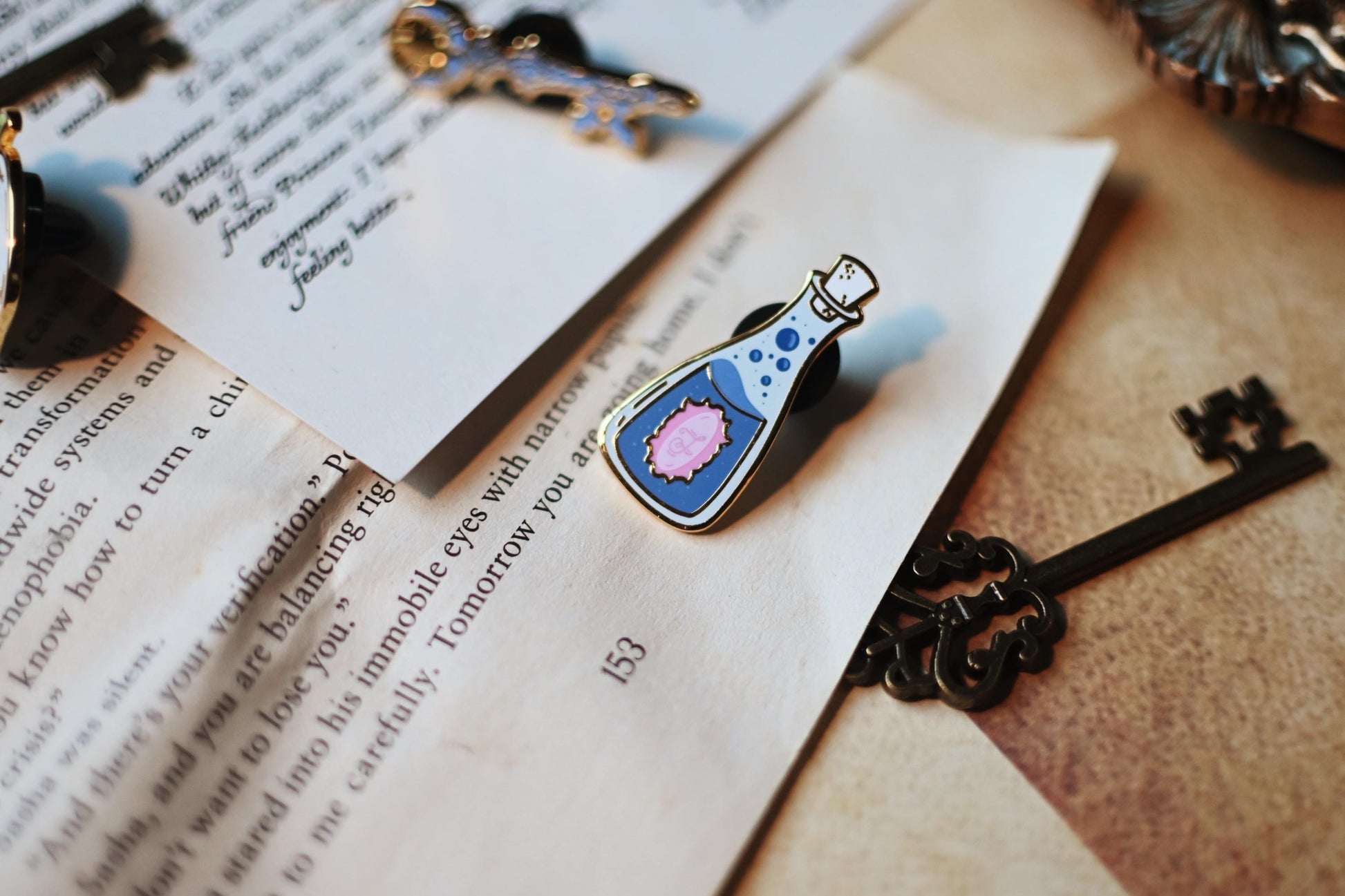 A close up show of the bottle pin, featuring the blue and pin detailing associated with the series. 