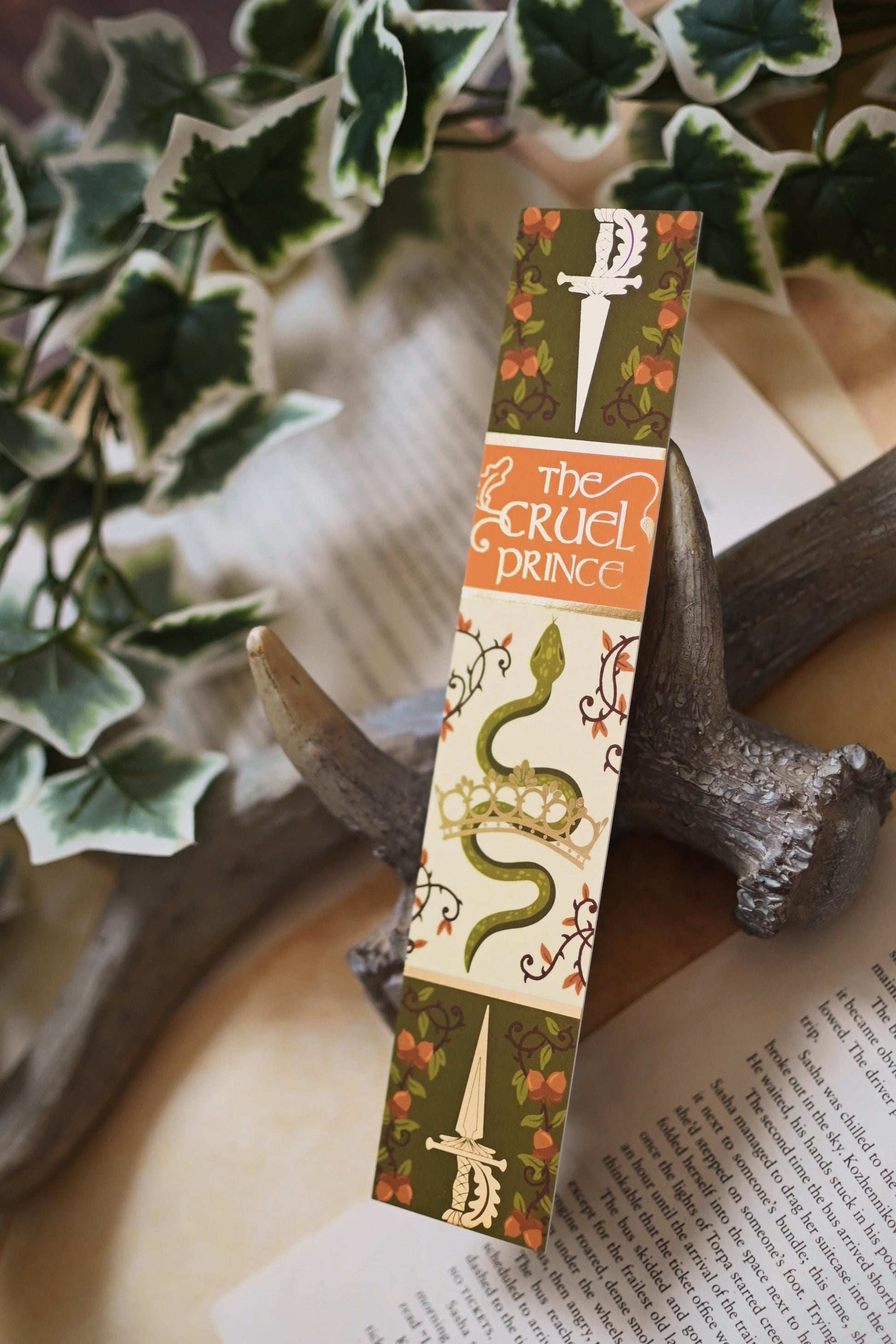 No One Designs The Cruel Prince inspired book spine design, the bookmark is propped up in full view to showcase all the details of the gold foil side of the bookmark.