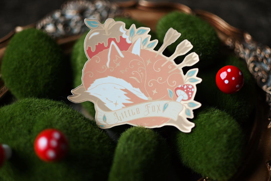 A foiled matte sticker depicting a character and a fox with a ribbon with 'Little Fox'.