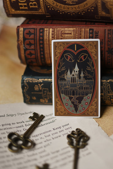 One Dark Window inspired sticker with castle design on a surface with vintage books and keys