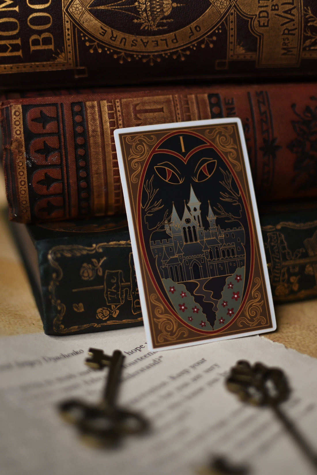 One Dark Window inspired sticker with castle design on a surface with vintage books and keys