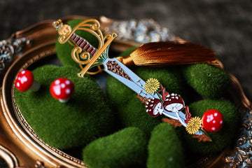 Inspired by Holly Black's The Folk of the Air series is a No One Designs enamel bookmark that features soft enamel detailing and a thick gold tassel.