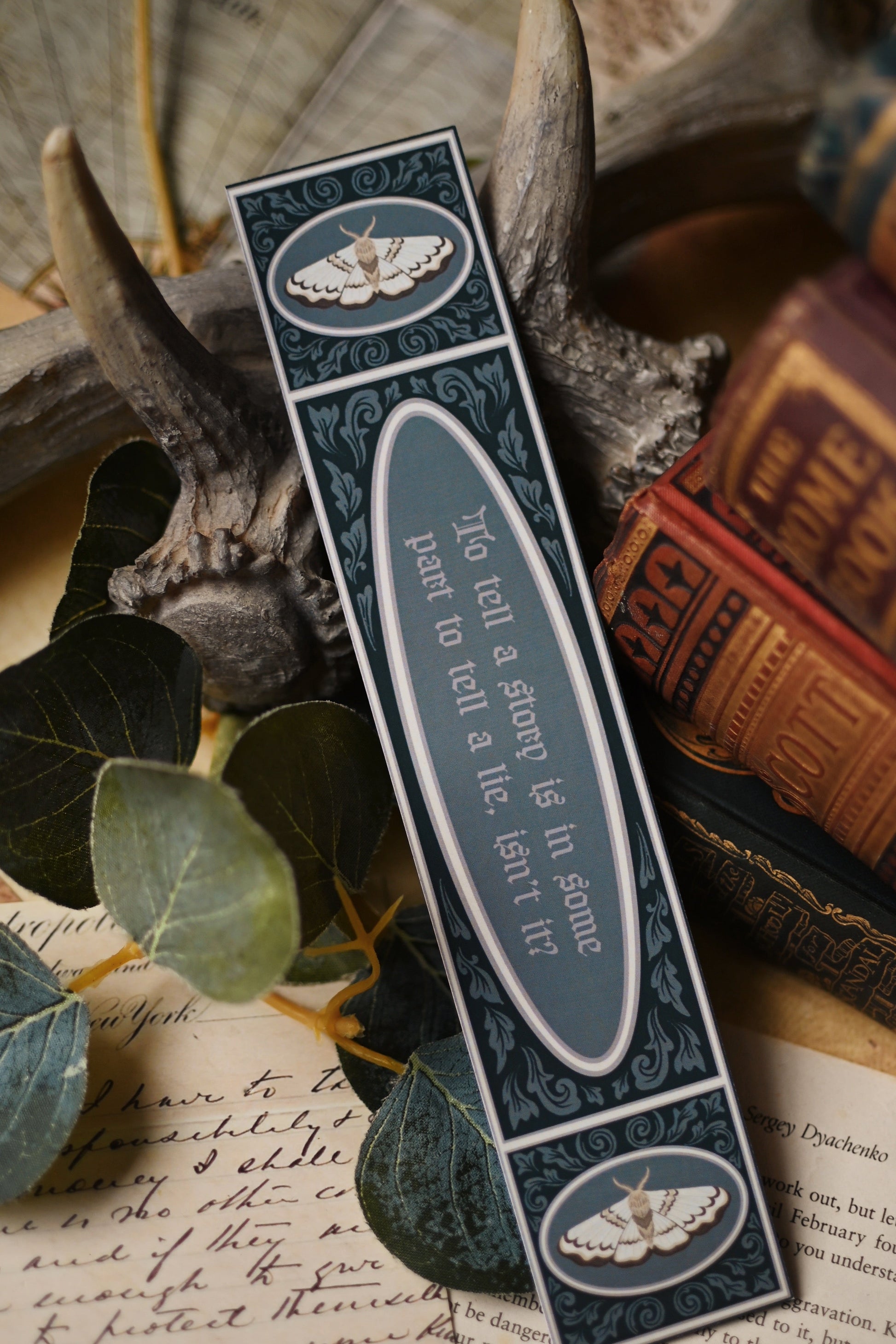 Decorative bookmark with text and decorative elements on a rustic background with books and leaves. The quote is: To tell a story is in some part to tell a lie, isn't it?